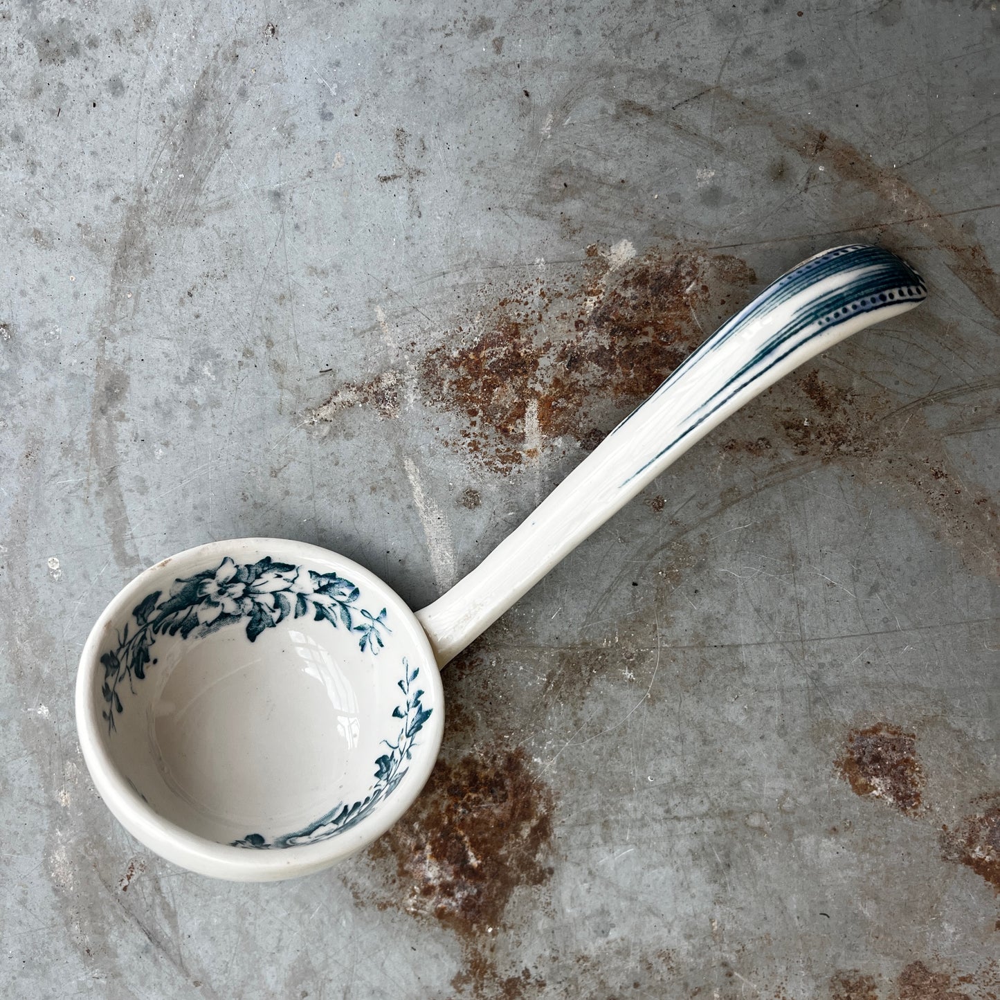 19th-century English transferware ceramic sauce ladle with traditional decorative patterning and a curved handle