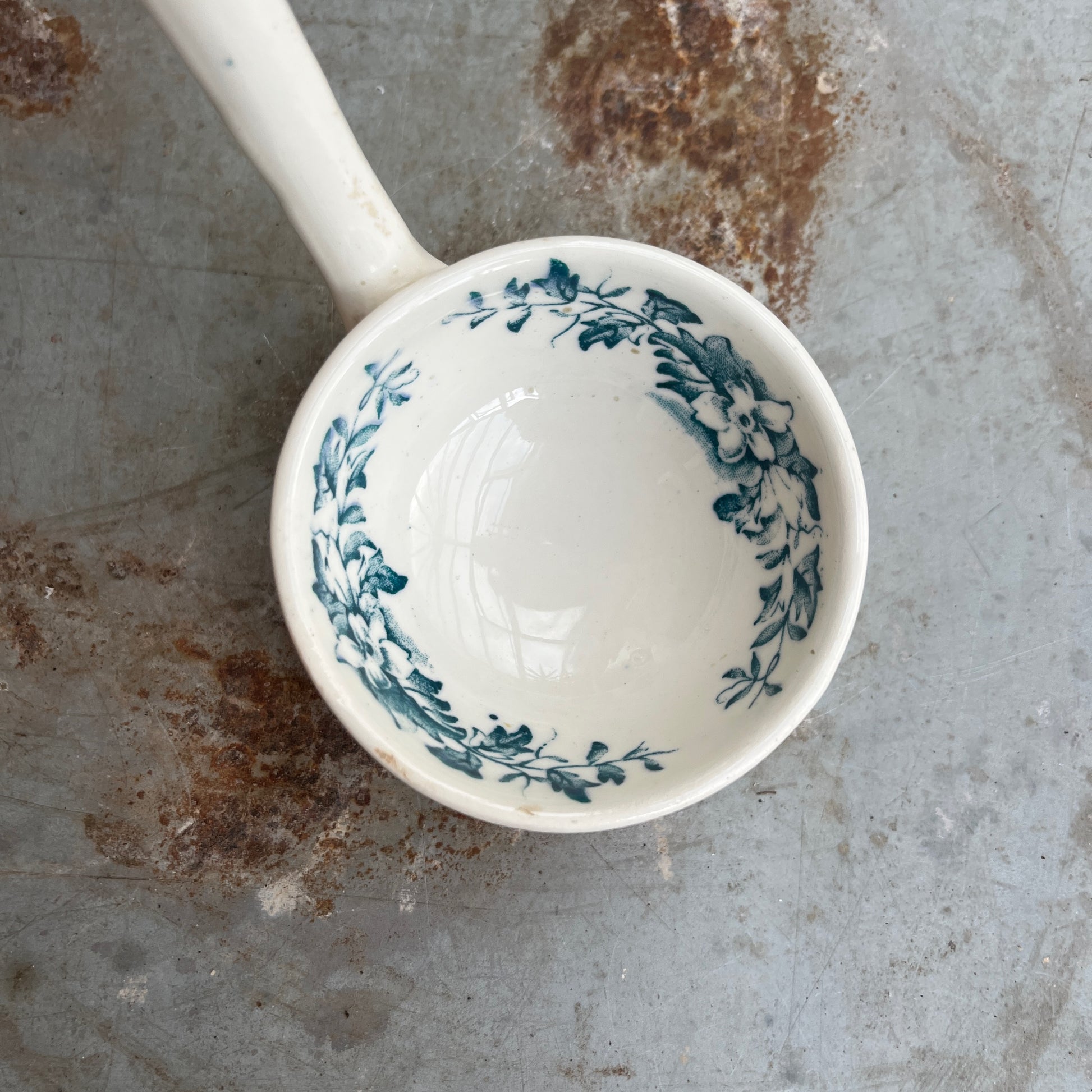 19th-century English transferware ceramic sauce ladle with traditional decorative patterning and a curved handle