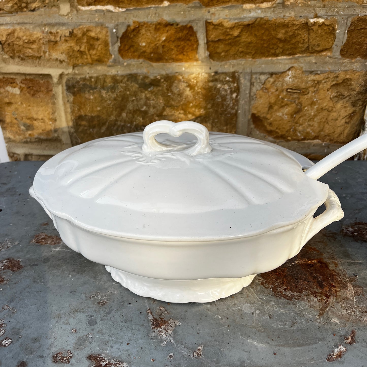 Vintage Belgian soup tureen with lid and matching ladle, featuring unusual white ceramic design and a traditional glazed finish.
