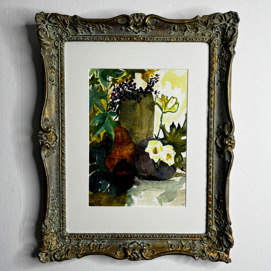 Still-life watercolor painting displayed in a vintage wooden frame, featuring softly rendered objects with delicate brushstrokes and muted, traditional colors.