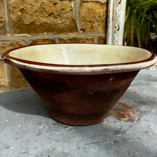 An antique English dairy bowl in soft cream-glazed earthenware with a classic wide, shallow shape and gently rounded sides. The bowl features a smooth glazed interior and a beautifully aged finish with subtle crazing and signs of use that enhance its authentic character.