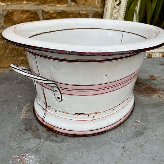 A large vintage French white enamel wash bowl, circa early 20th century, featuring a wide, deep basin. The bowl is adorned with delicate pink stripes,  with a smooth white enamel finish showing minor chips and rust spots, characteristic of its aged, rustic charm.