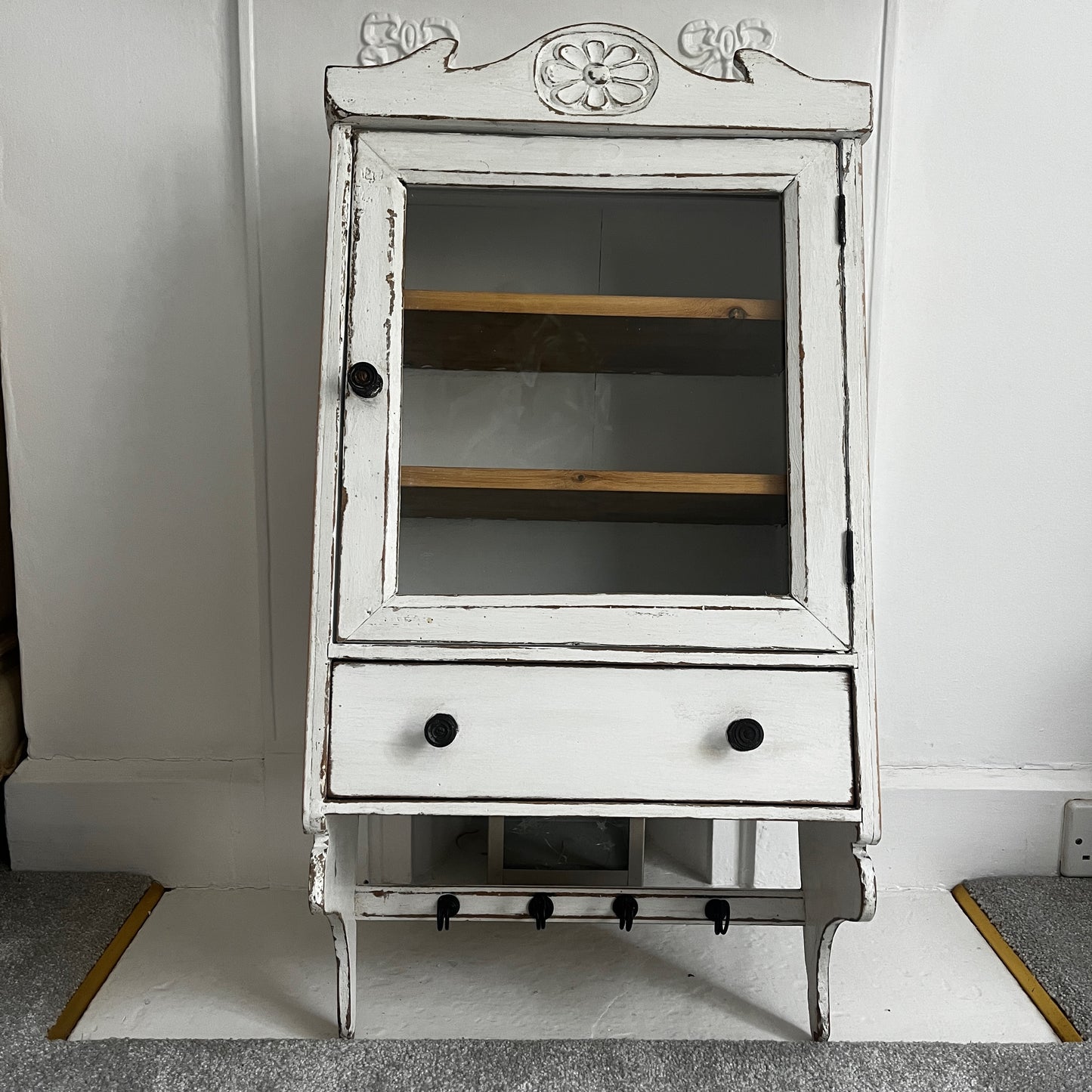 A French wall cupboard with a glazed glass door, two interior shelves, a single drawer, and practical hooks beneath. Its compact proportions and timeless rustic character make it ideal for use as a kitchen, bathroom, or hallway cabinet.