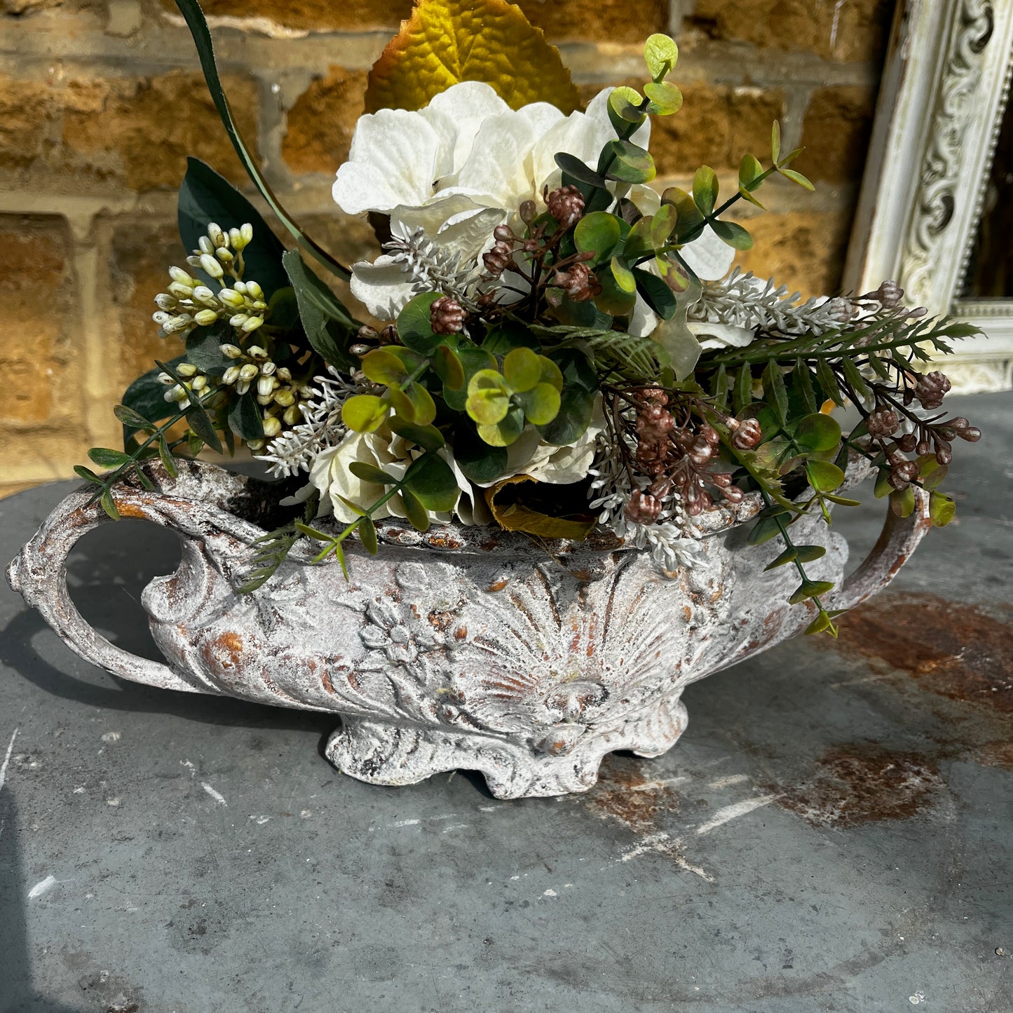 An antique Rococo-style cast iron jardiniere featuring an ornate decorative design with scrolling details, curved handles, and an aged, weathered finish