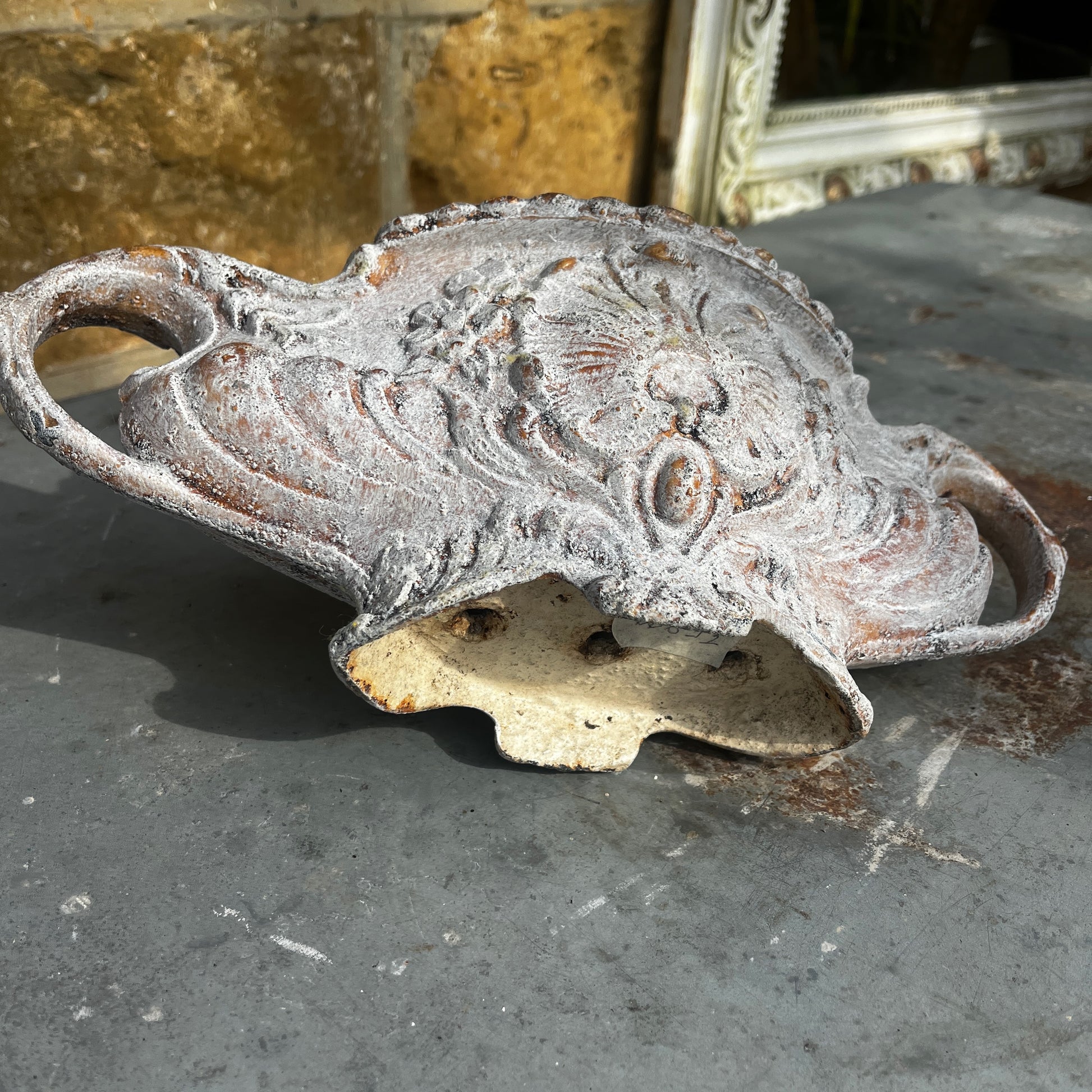 An antique Rococo-style cast iron jardiniere featuring an ornate decorative design with scrolling details, curved handles, and an aged, weathered finish