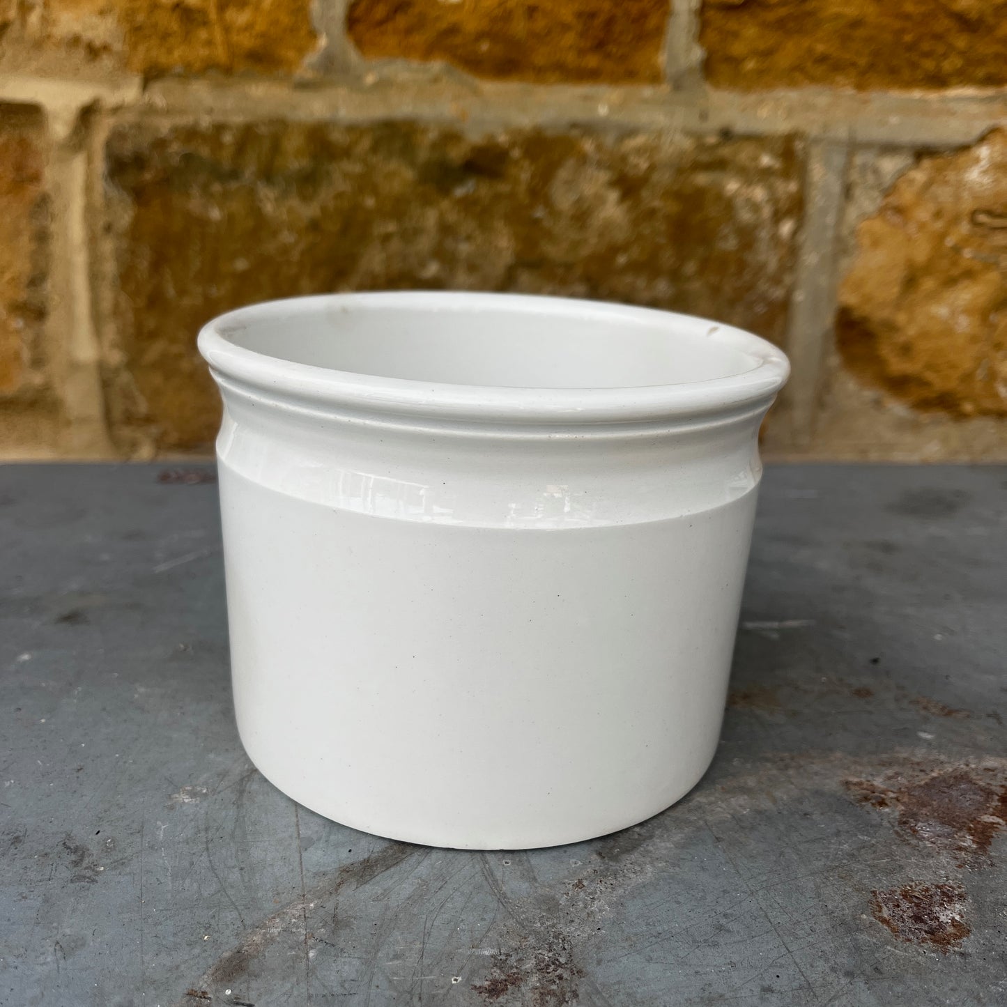 A vintage white ceramic storage pot with a simple cylindrical shape and a rolled rim, finished in a smooth glossy glaze. Its clean, understated design reflects traditional farmhouse and apothecary pottery, making it ideal for storing kitchen utensils, herbs, or small household items.