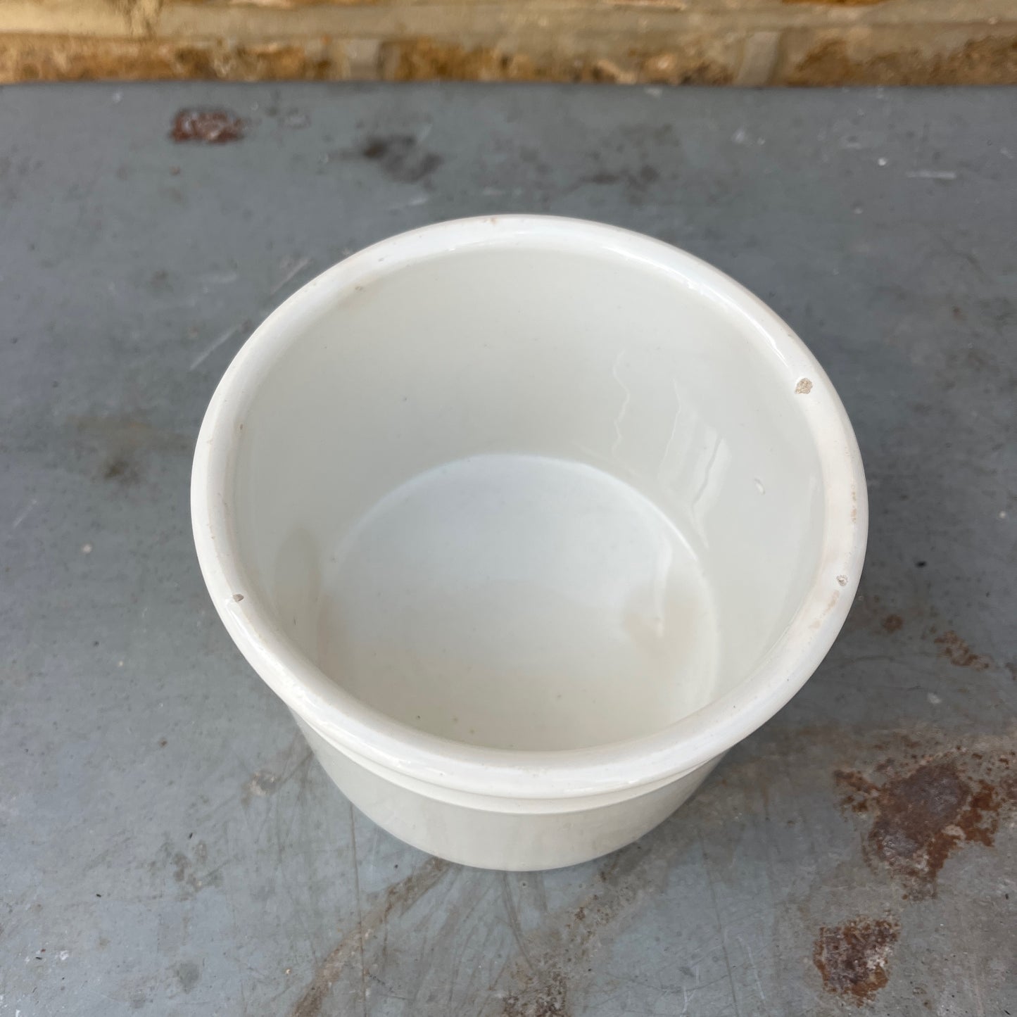 A vintage white ceramic storage pot with a simple cylindrical shape and a rolled rim, finished in a smooth glossy glaze. Its clean, understated design reflects traditional farmhouse and apothecary pottery, making it ideal for storing kitchen utensils, herbs, or small household items.
