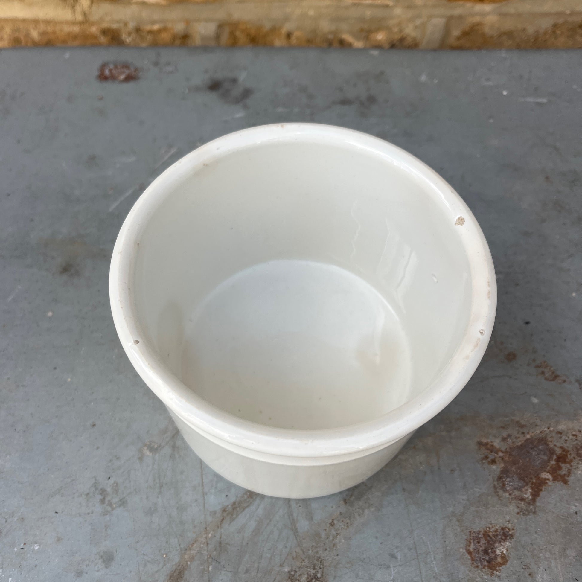 A vintage white ceramic storage pot with a simple cylindrical shape and a rolled rim, finished in a smooth glossy glaze. Its clean, understated design reflects traditional farmhouse and apothecary pottery, making it ideal for storing kitchen utensils, herbs, or small household items.