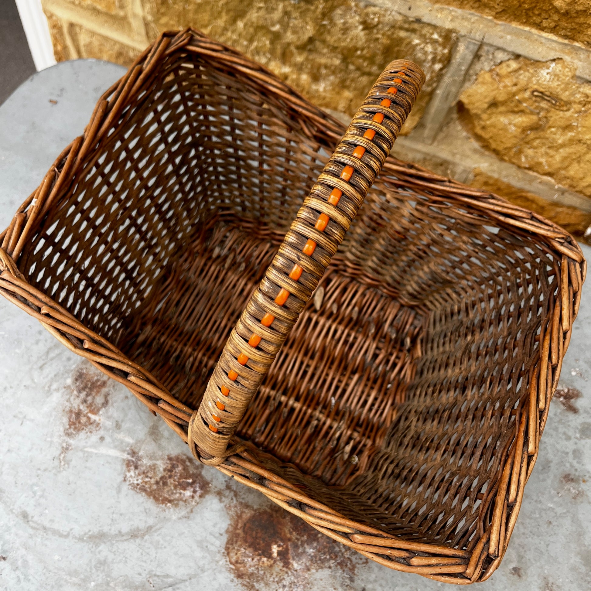 Vintage wicker basket with woven construction and orange detailing