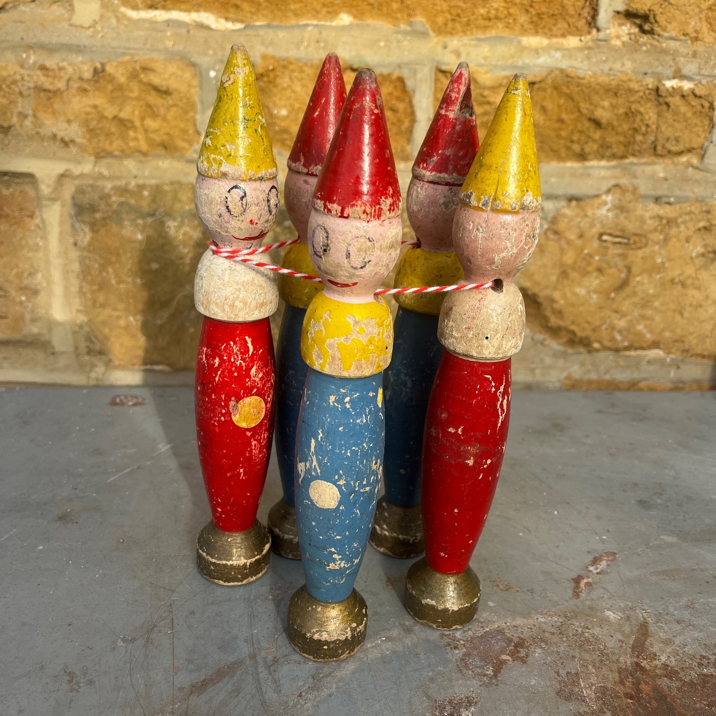 A set of five vintage wooden toy skittles with painted red, yellow, and blue bodies.