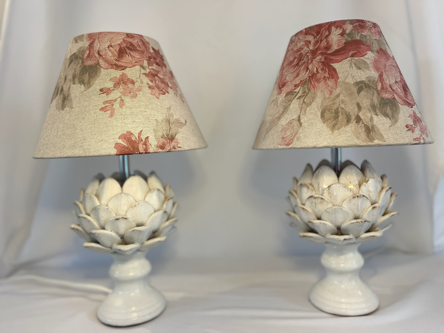 A pair of artichoke lamp bases hosting handmade shades made from a Cabbages & Roses style linen.