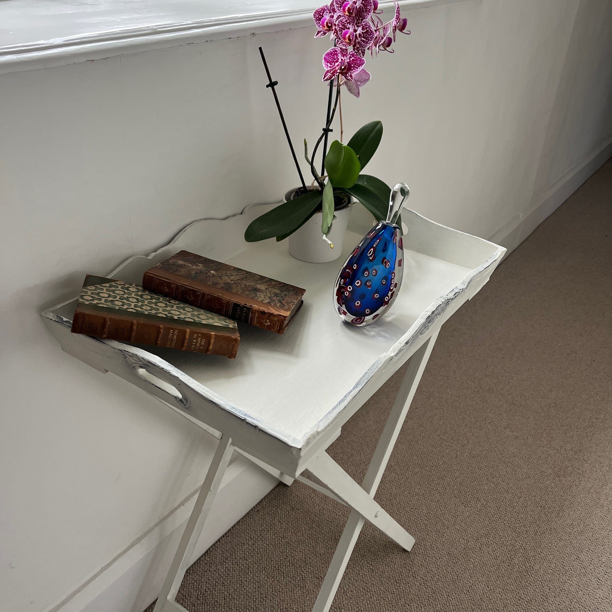 A white butler‚Äôs tray, which has been painted and distressed, featuring a rectangular shape with raised edges and two sturdy handles on either side, designed for versatile serving or display.