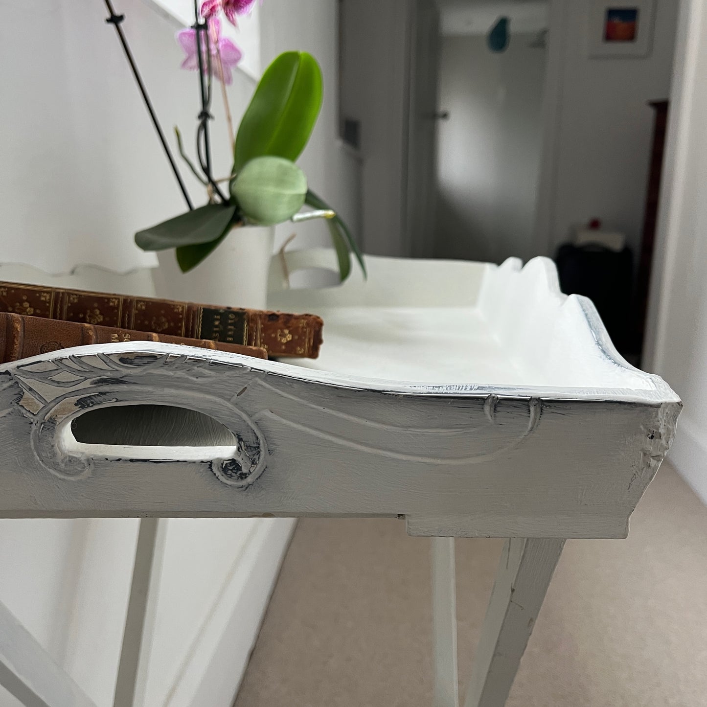 A white butler‚Äôs tray, which has been painted and distressed, featuring a rectangular shape with raised edges and two sturdy handles on either side, designed for versatile serving or display.