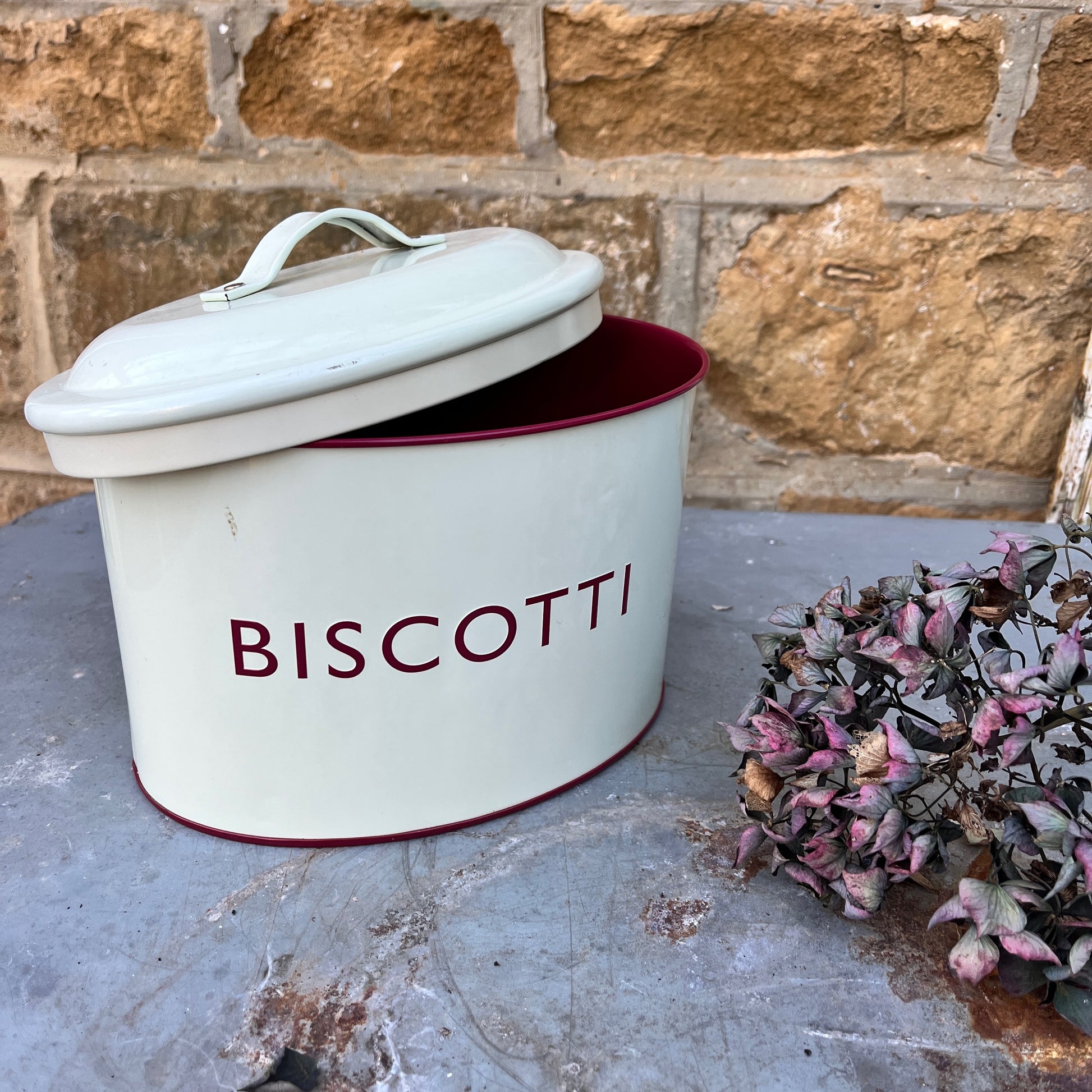 Two enamel biscuit tins with the words Amaretti and Biscotti on the front
