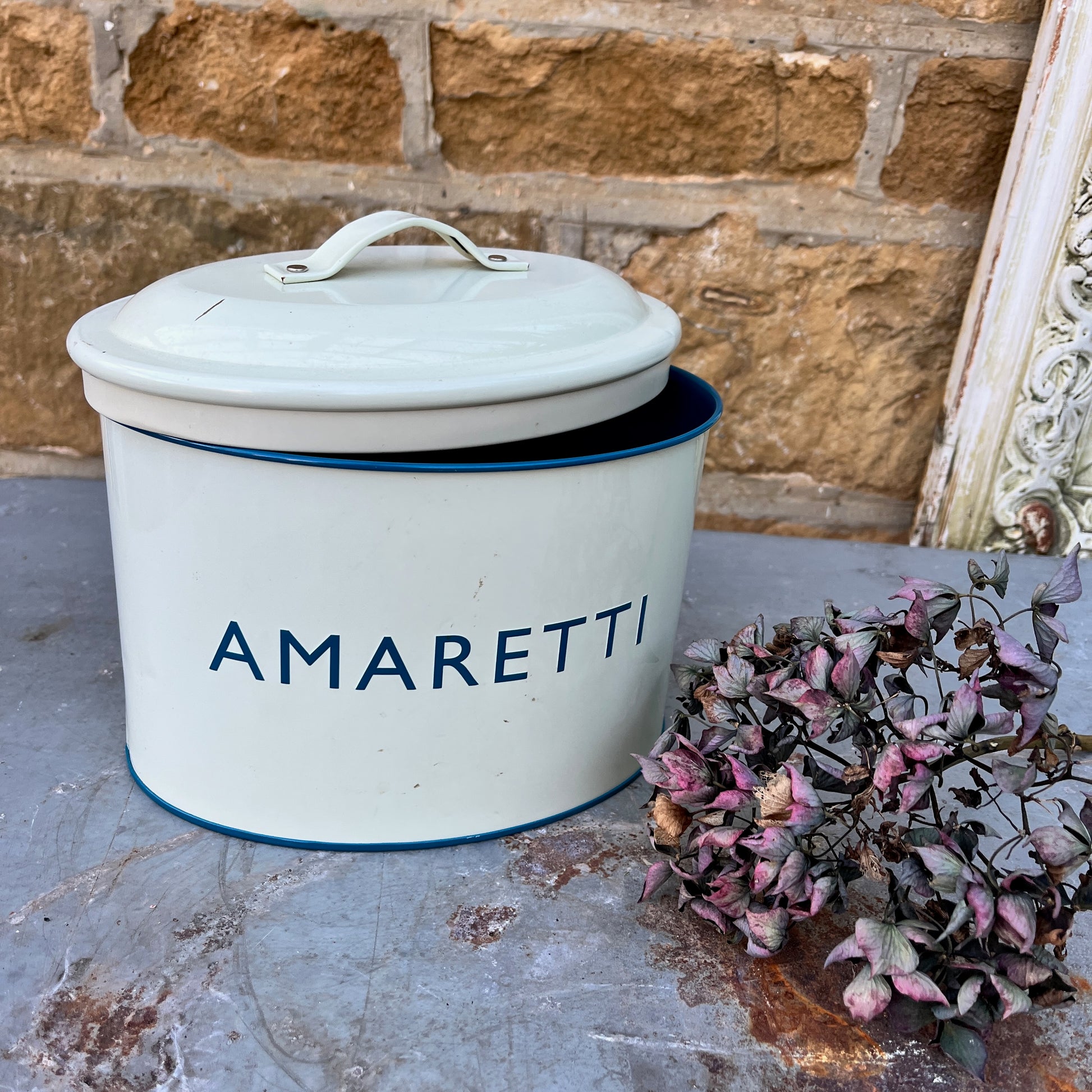 Two enamel biscuit tins with the words Amaretti and Biscotti on the front