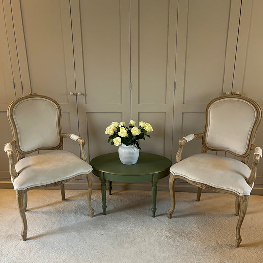 Pair of French-style carver chairs, freshly upholstered in luxurious cream velvet, showcasing ornate carvings and a refined, elegant design.