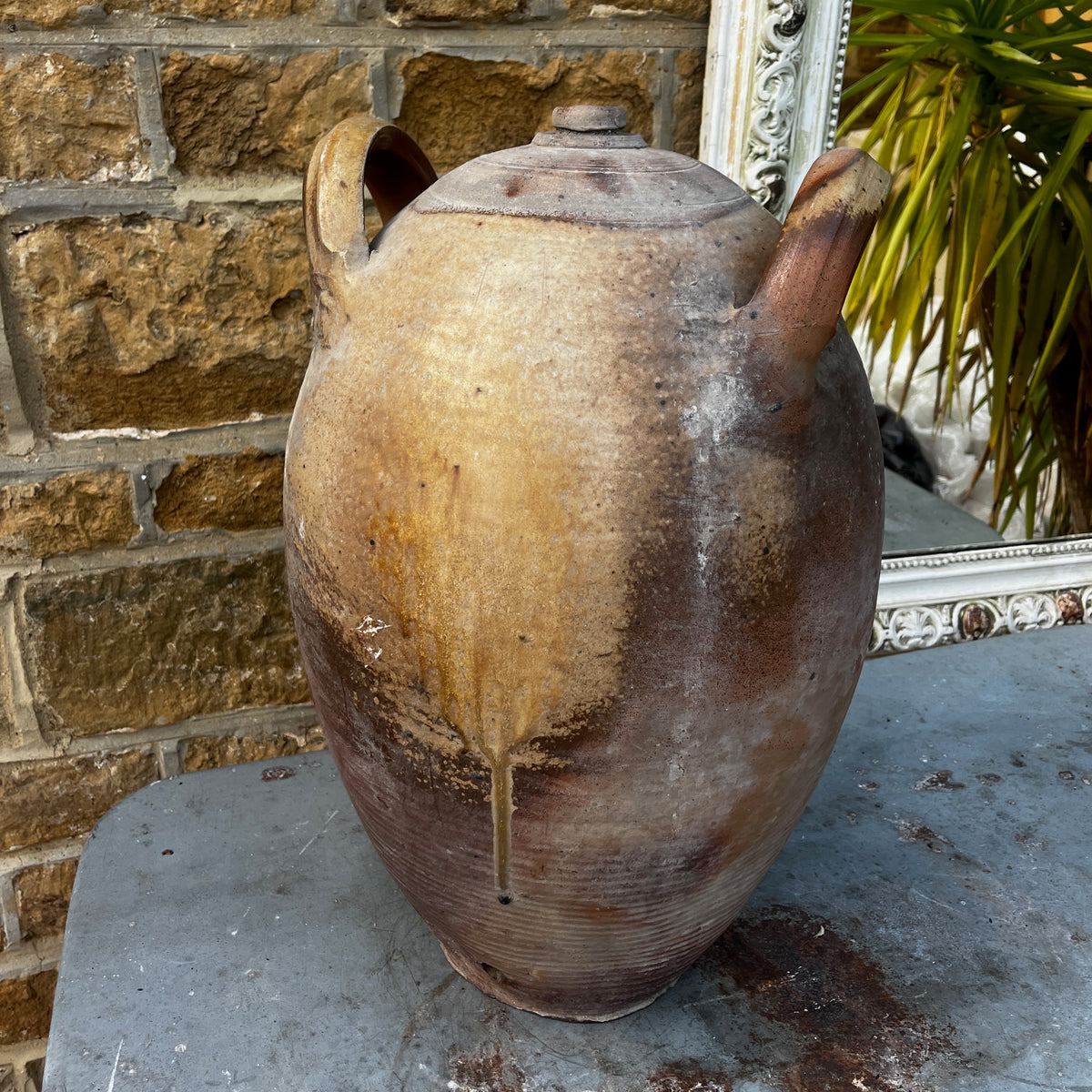 A large handmade ceramic amphora-style vase with a lid, featuring a rustic earthy brown and beige glaze
