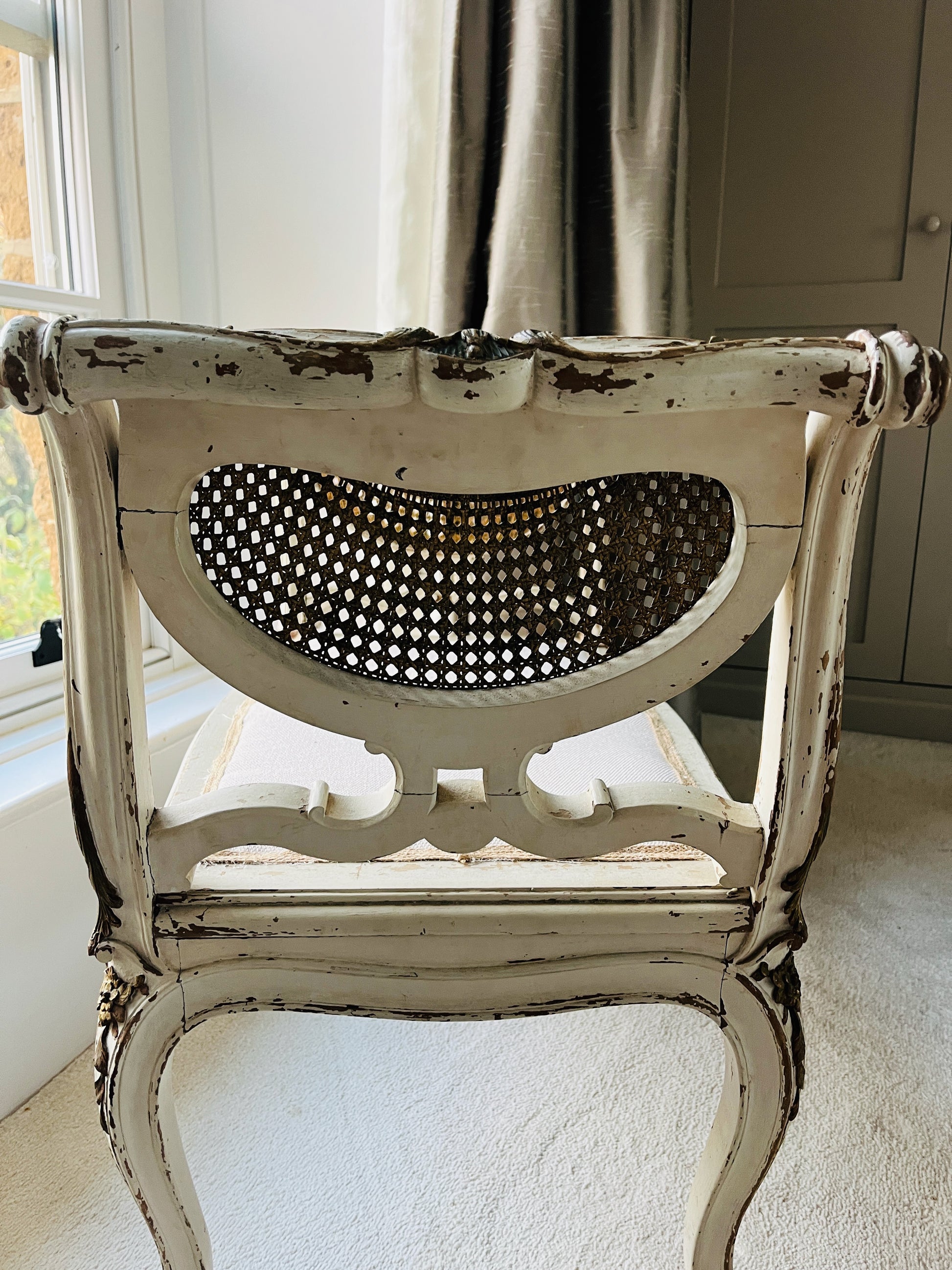 Antique French window seat featuring elegant caned arms and a newly upholstered seat, combining classic craftsmanship with timeless sophistication