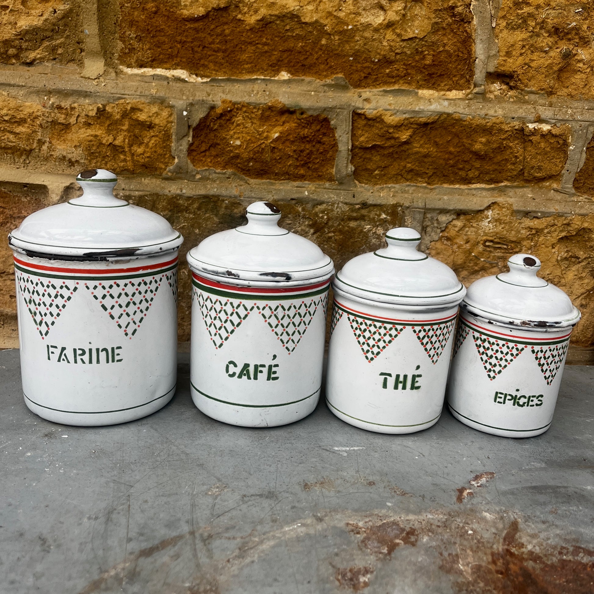 Four vintage white ceramic canisters with lids for flour, coffee, tea, and spices, decorated with green geometric patterns and orange stripes.