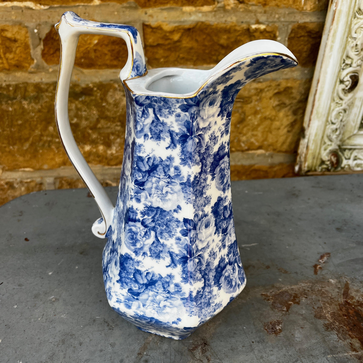 A vintage blue and white floral patterned ceramic pitcher with a curved handle, and  long spout.