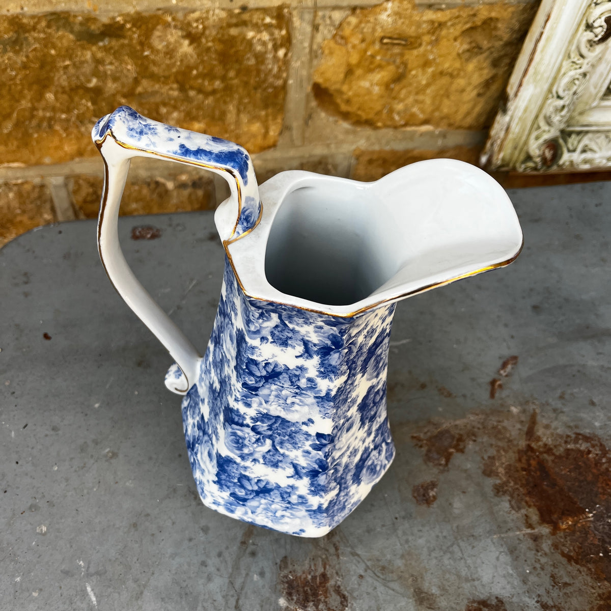 A vintage blue and white floral patterned ceramic pitcher with a curved handle, and  long spout.