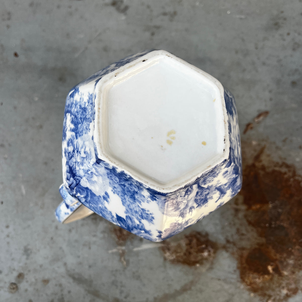 A vintage blue and white floral patterned ceramic pitcher with a curved handle, and  long spout.