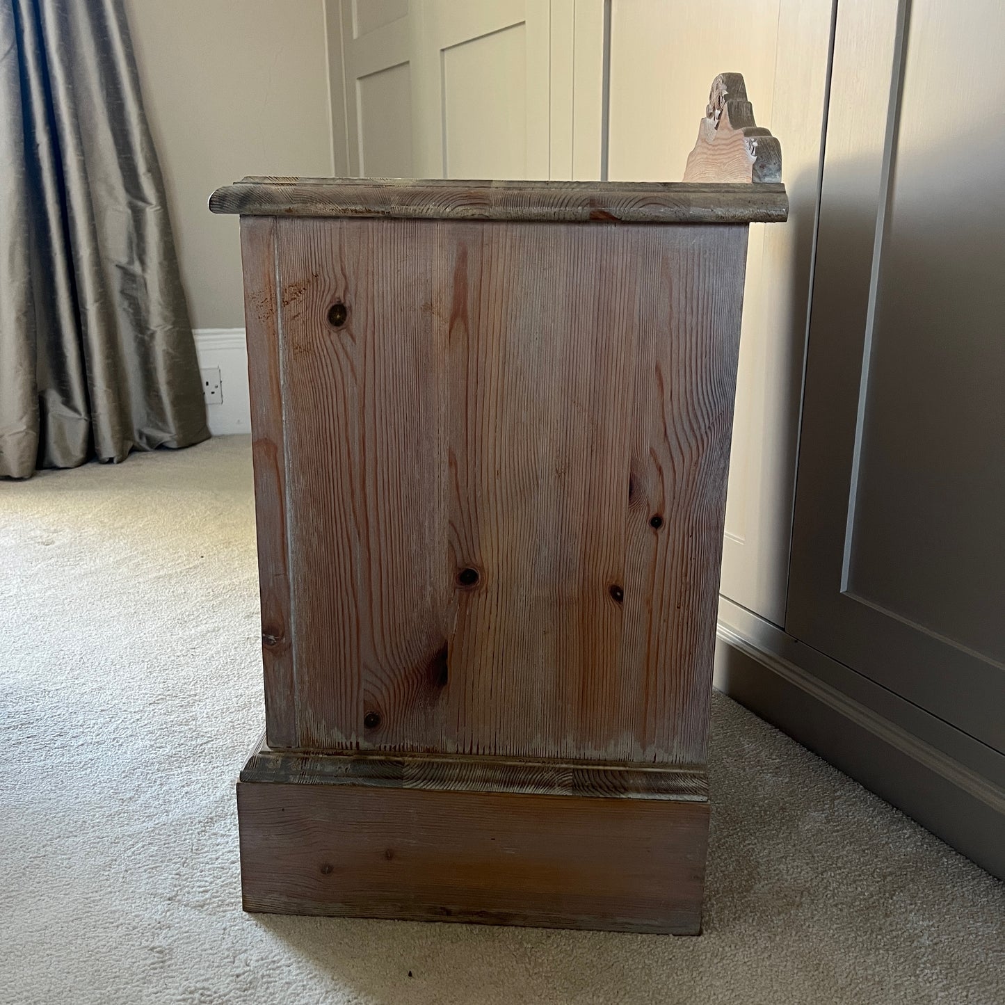 A pair of simple pine bedside tables with a natural wood finish, featuring decorative detail on the front, a single drawer with a ornate handle, and an open lower shelf, exuding rustic charm and functionality.