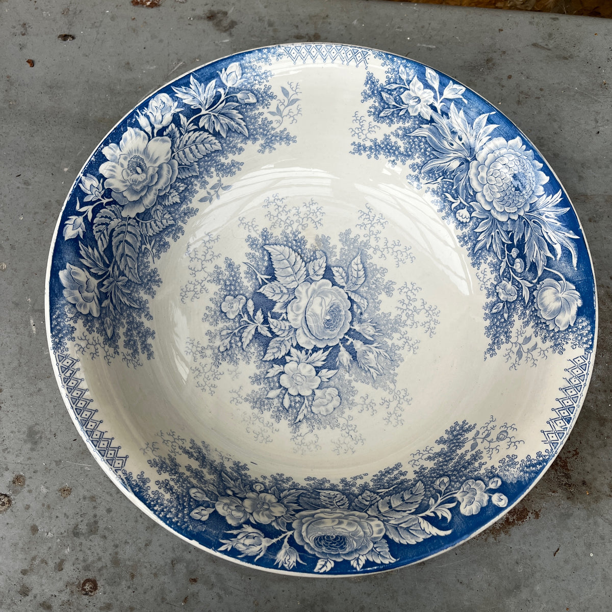 A blue and white ceramic pitcher with a floral pattern, placed inside a matching deep bowl.