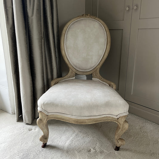 A Victorian occasional chair, recently reupholstered in luxurious cream velvet, featuring ornate wooden carvings along the frame and elegant curved legs, exuding a blend of vintage charm and modern sophistication.