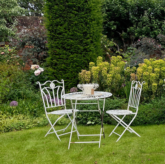 Vintage white bistro set for two, featuring a charming table and chairs with a decorative design, perfect for outdoor or indoor dining